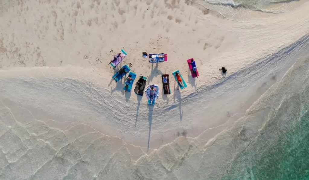 Women gathered on a white sandbank in Mozambique, surrounded by clear turquoise ocean