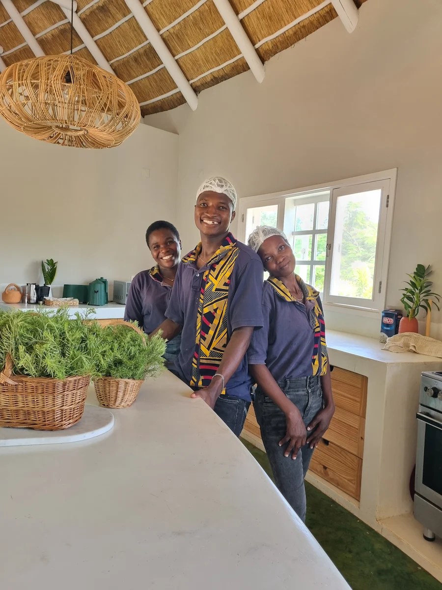 Staff at Humbi Farm in Mozambique wearing colorful capulanas, standing together in a welcoming tropical setting, representing local culture and hospitality